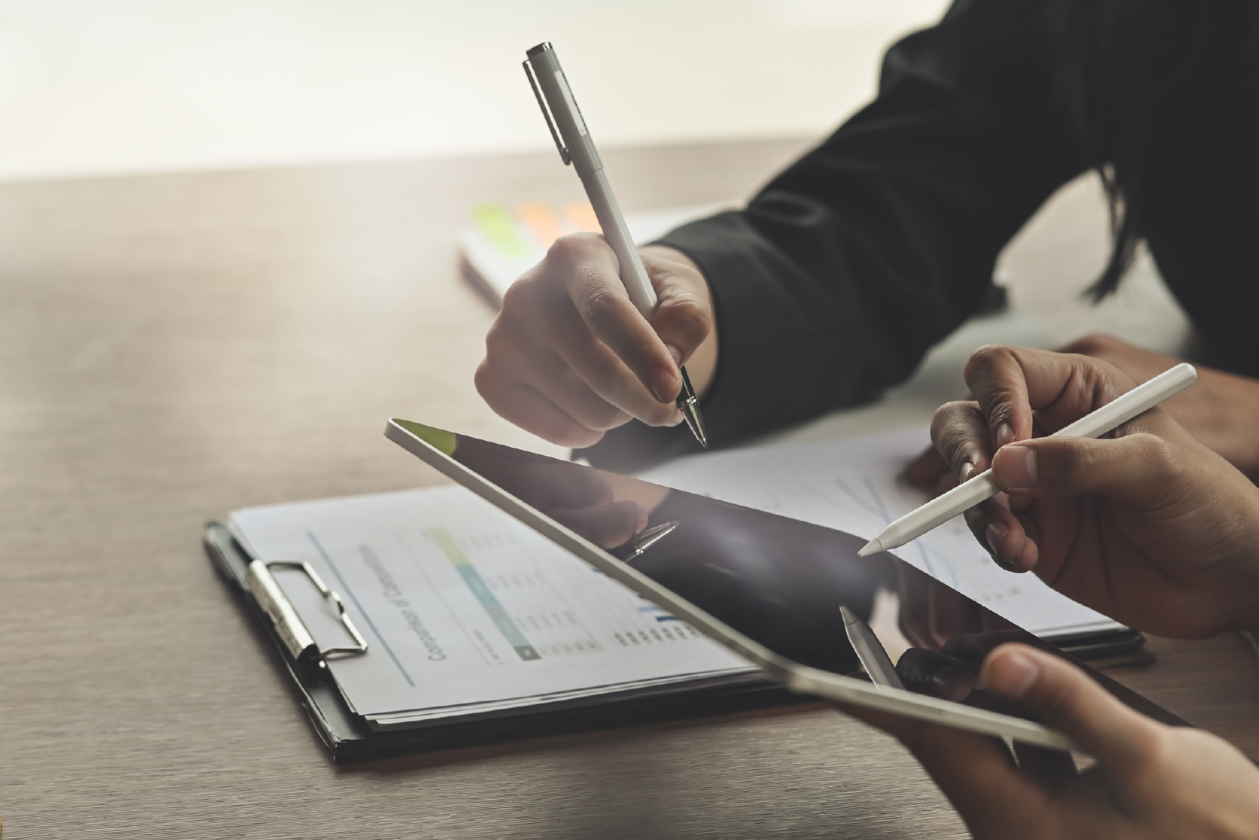 People holding pens and pointing to a tablet